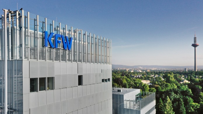 Drohnenaufnahme der KfW-Niederlassung Frankfurt. Links im Bild das Haupthaus mit KfW Logo, rechts Ausblick auf den Palmengarten und in der Ferne ein Fernsehturm.