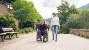 A woman walks alongside a man in a wheelchair