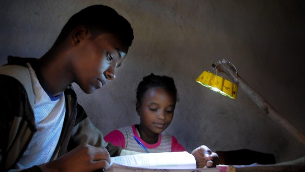 School children doing their homework, illuminated by a Little Sun solar lamp