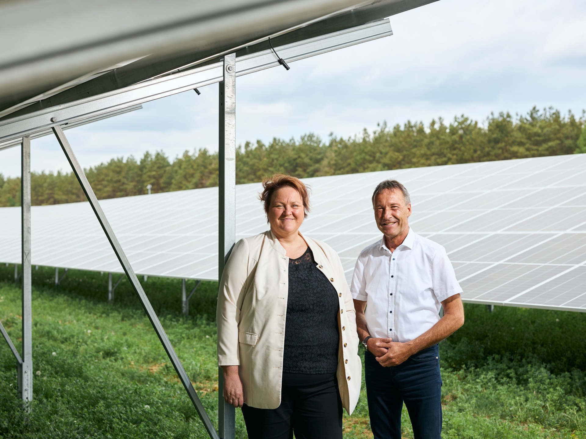 Frau und Mann mit Solaranlage im Hintergrund