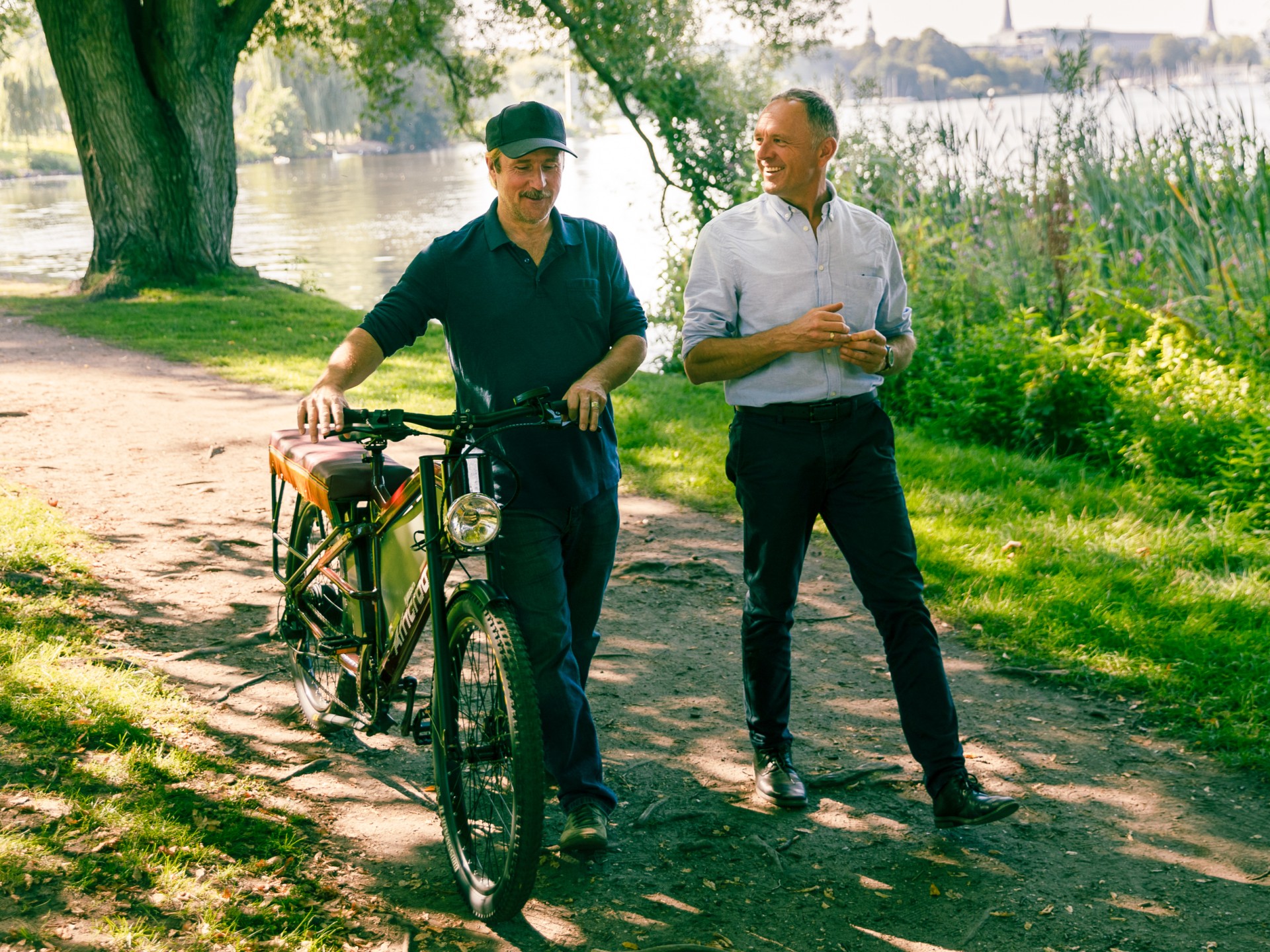 Bjarne Mädel schiebt das African E-Bike. Er und Jürgen Perschon unterhalten sich. 