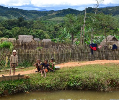 Kinder in einem laotischen Dorf spielen am Fluss.