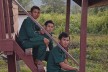Drei Rangers sitzen auf einer Treppe in einem laotischen Dorf.