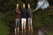 Portrait of three men, standing barefoot in a small river
