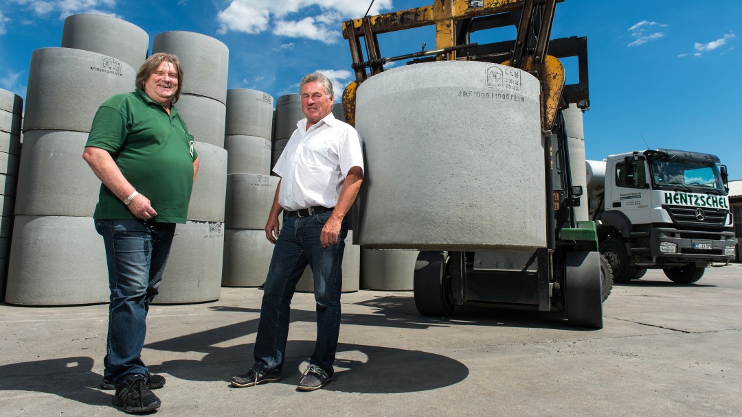 Two building contractors with concrete rings in the background 