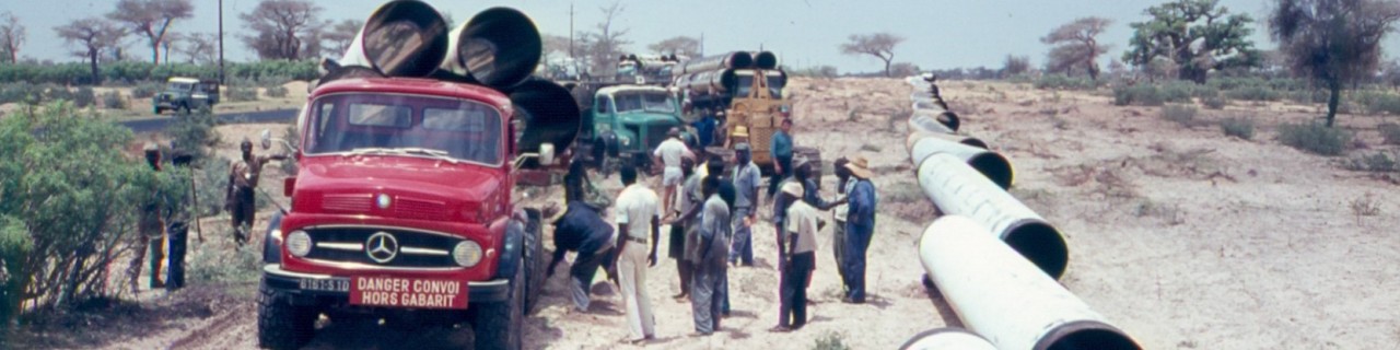 Roter LKW mit vielen Menschen an einem Wasserrohr