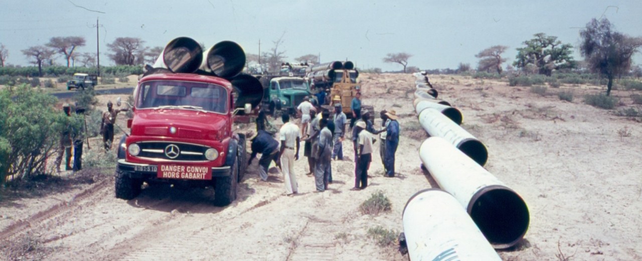 Red truck with many people on a water pipe