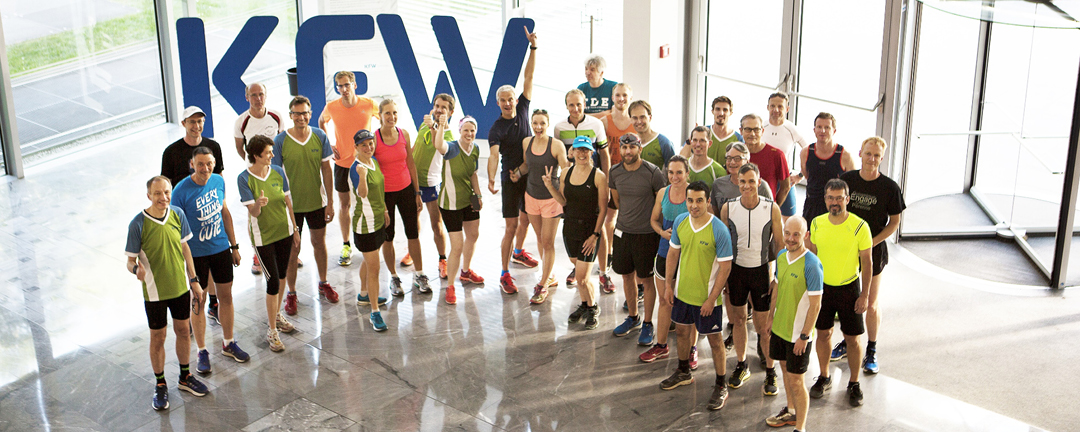 Ein Gruppenbild von der Betriebssportgruppe Triathlon. Die Personen haben ihre Sportsachen an und gehen danach im Anschluss eine Runde im Grüneburgpark laufen.