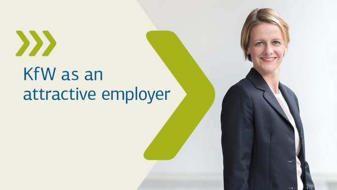 A woman stands with her arms folded in front of the glass door of an office