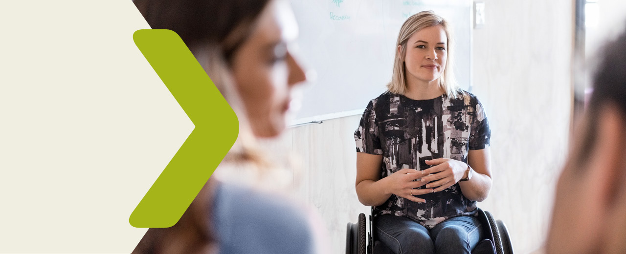 Portrait of a young woman in a wheelchair together with two other peope in a office