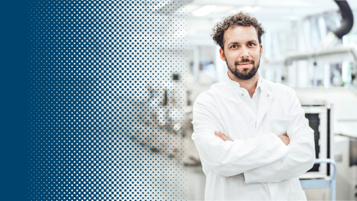 Ein Wissenschaftler steht mit weißem Kittel in einem Labor vor Maschinen