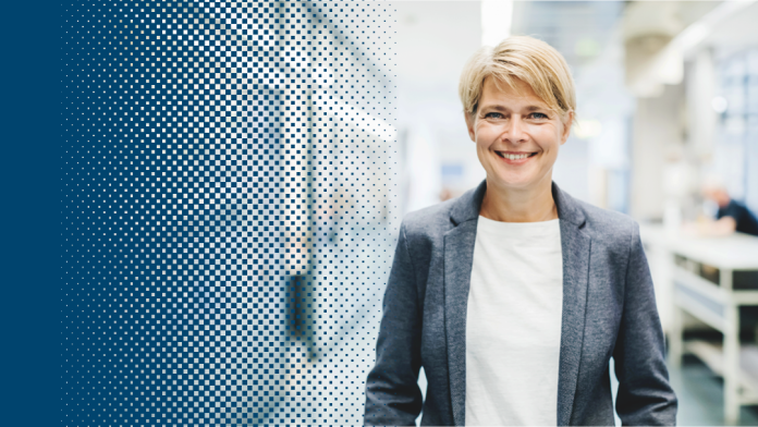 Woman in business clothing standing in front of devices