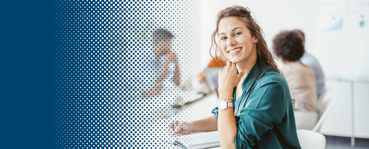 Woman sitting smiling at a laptop in a meeting room