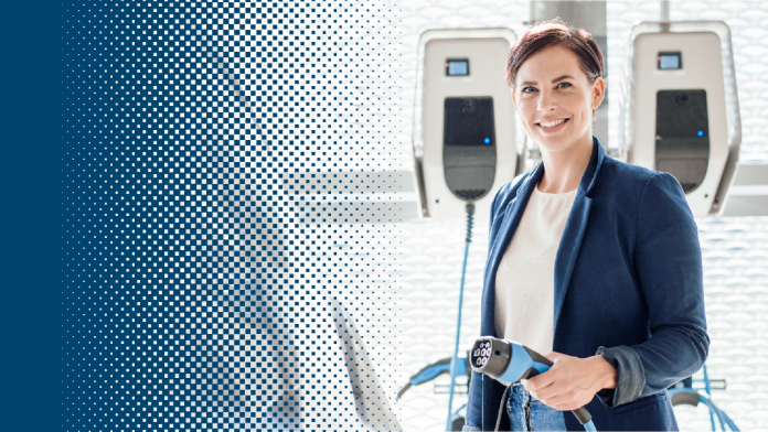 Woman in front of e-car charging station with a charger