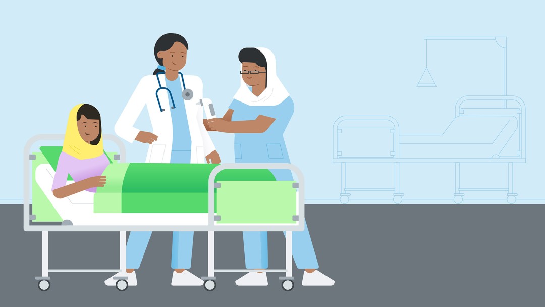 A person lies in a hospital bed, next to two female doctors