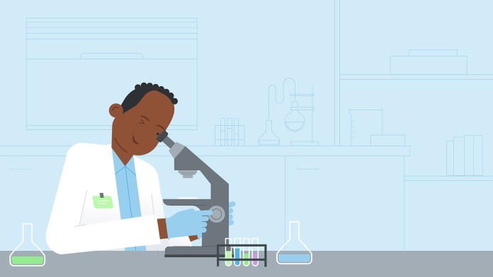 A person in a white coat looks into a microscope