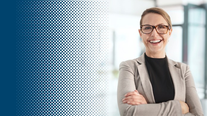 Woman with blazer stands with folded arms and smiles into the camera