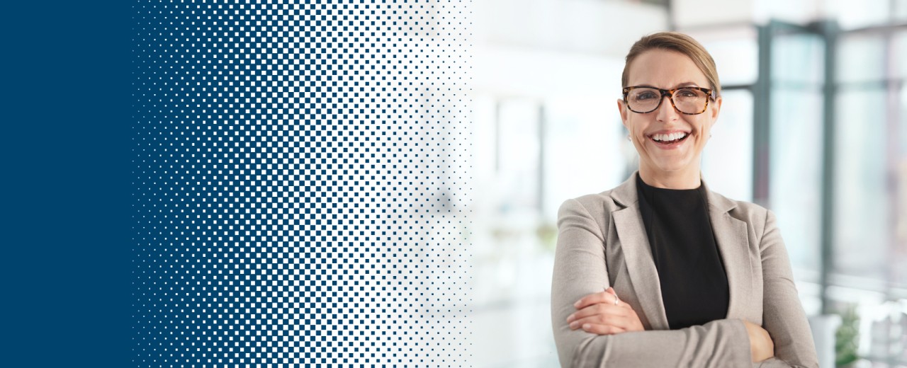 Woman with blazer stands with folded arms and smiles into the camera