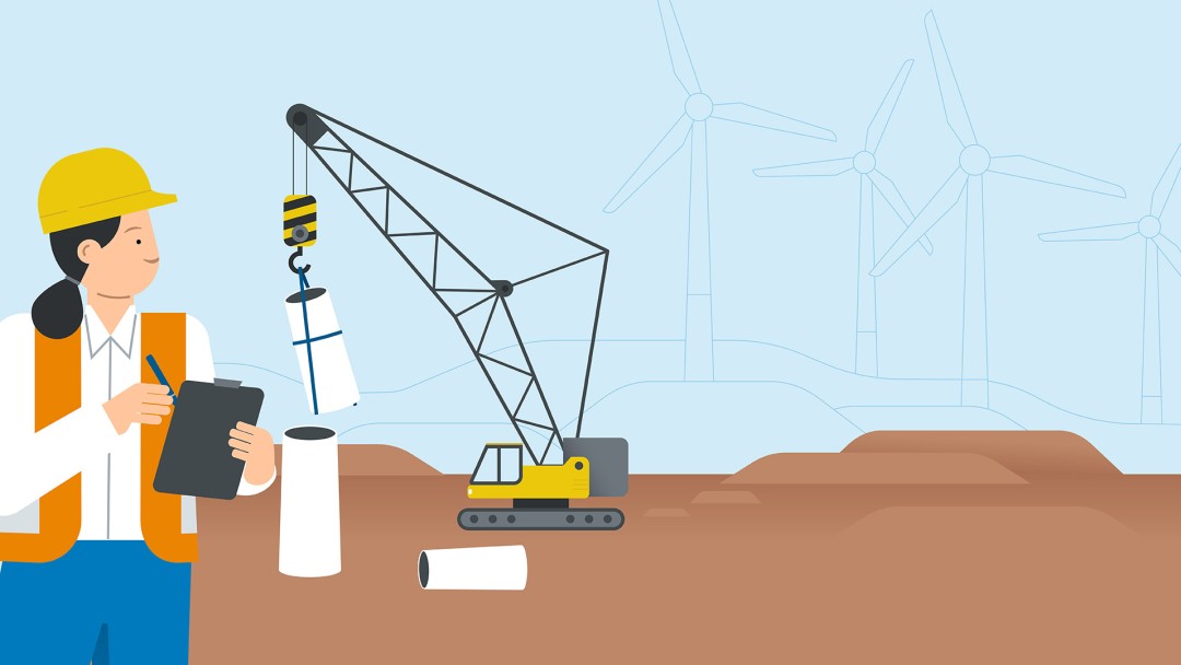 A worker stands with a clipboard in front of a crane erecting a wind turbine
