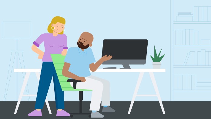 Two people standing in front of a desktop screen
