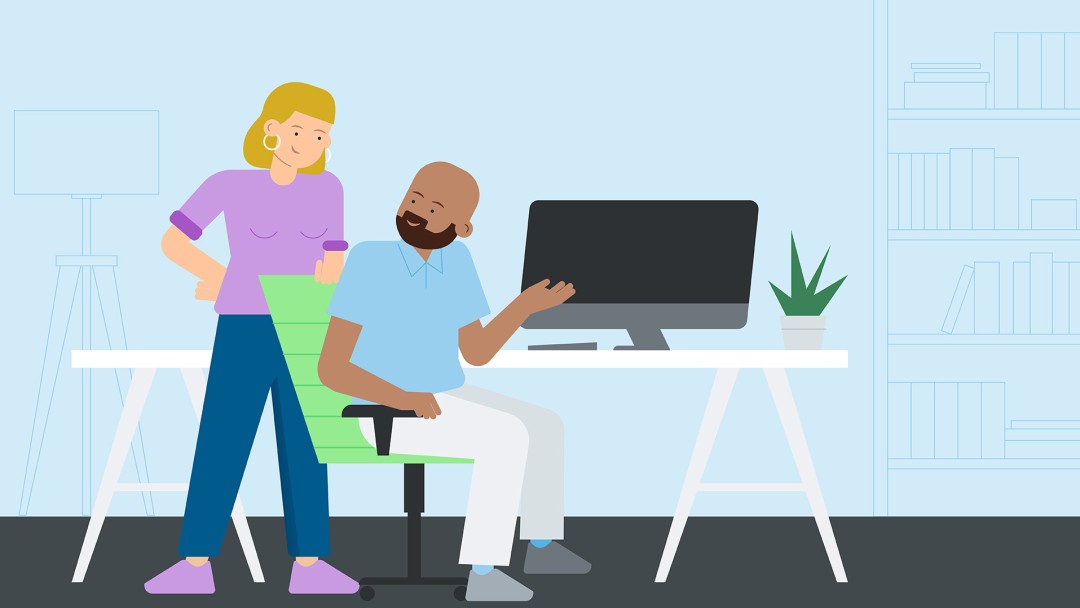 Two people standing in front of a desktop screen