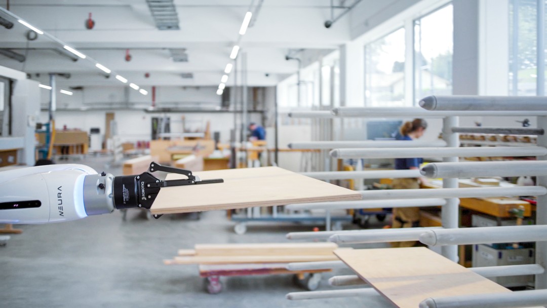 Ein Industrieroboter greift eine Holzplatte in einem Setting moderner Fertigung. Zum Audrcuk kommen hier Automatisierung und Industrie 4.0 in der Produktion.