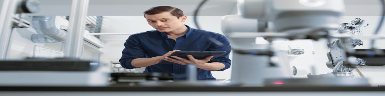 Ein Mann, womöglich ein Ingenieur bedient ein Tablet. Er steht in einem Hightech-Labor vor einem Roboterarm. Die Themen Digitalisierung, Robotik und industrielle Innovation sind hier zentral.