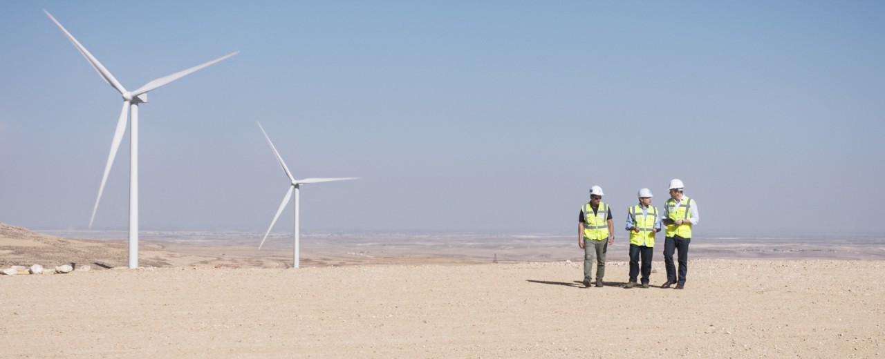 Windkraftanlage in Wüstenlandschaft mit Technikern. Themen sind erneuerbare Energien, nachhaltige Energieerzeugung und Energiewende.