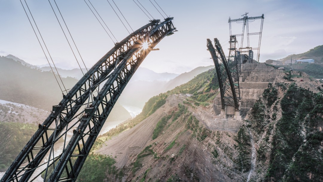 Großbaustelle für Brückenbau in einer Gebirgsregion. Verbildlicht sind hier die Themen Infrastrukturentwicklung, Bauwesen und internationale Projekte.
