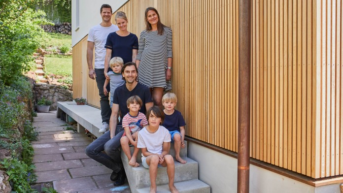 Familie mit kleinen Kindern vor Hauswand