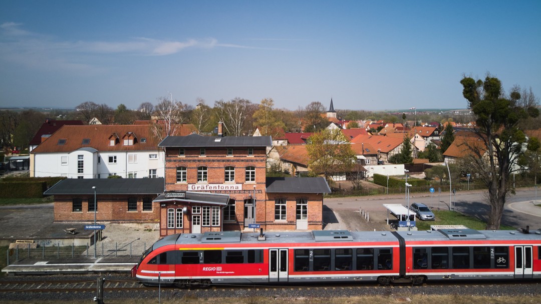 Ehemaliger Bahnhof mit rotem Zug auf den Gleisen