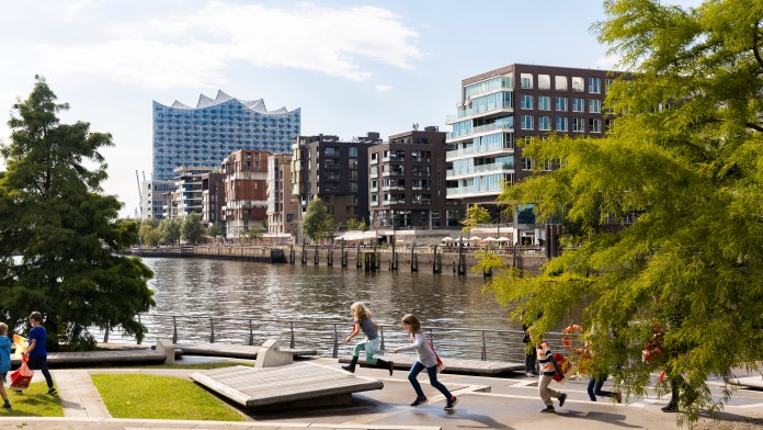 Blick auf zwei spielende Kinder vor dem Hintergrund der Hamburger Hafen-City und der Elbphilharmonie