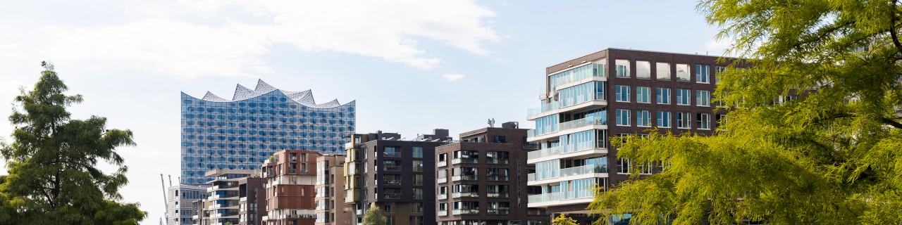 Blick auf zwei spielende Kinder vor dem Hintergrund der Hamburger Hafen-City und der Elbphilharmonie