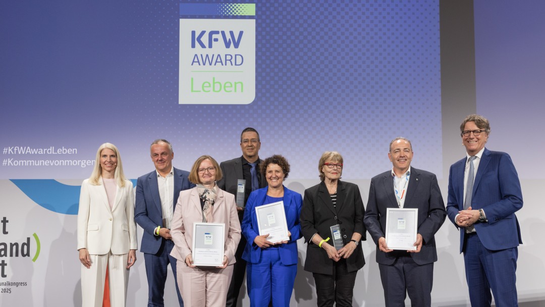Preisverleihung des KfW Award Leben in der Kategorie „Bezahlbares und flächeneffizientes Wohnen“. Gruppenfoto der Gewinner auf der Bühne.