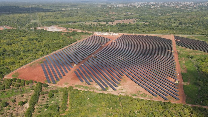 Aerial view of a solar power plant in Africa set against a green landscape