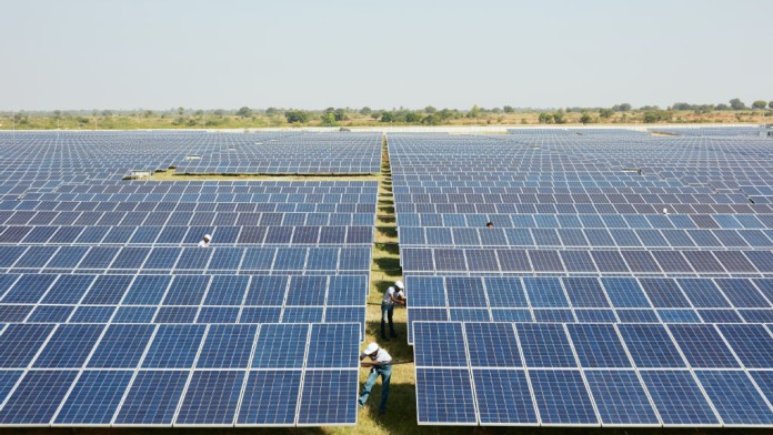 Landscape shot of a large solar power plant in India while workers maintain the facility