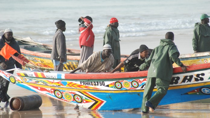 Fischer schieben ein Boot an den Strand