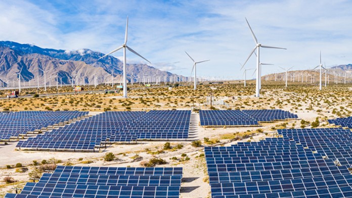 Solarpark vor Windpark mit Bergen im Hintergrund