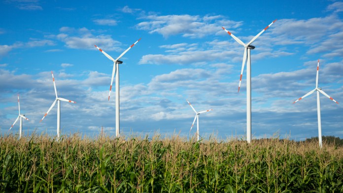Dies ist ein Bild von einem Windpark mit sechs Windrädern auf einem Feld.