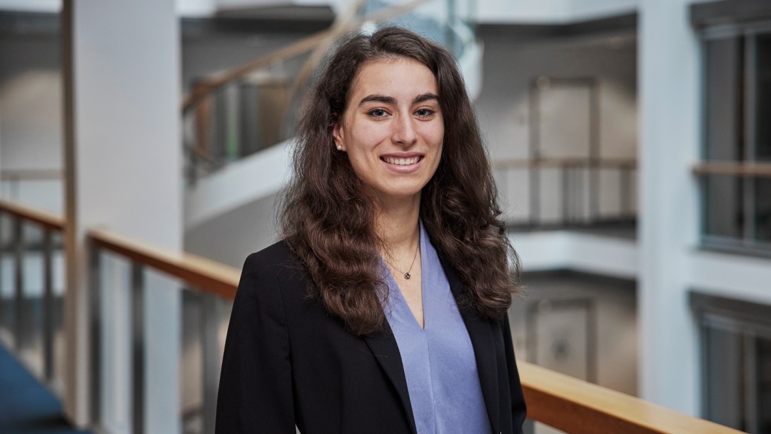 Portraitaufnahme von Jasmin Capka in der Ostarkade in Frankfurt, sie trägt eine hellblaue Bluse und einen dunklen Blazer