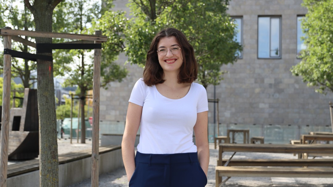 Portraitbild von Berit Rohde, Mitarbeiterin aus dem IT-Bereich KfW. Sie trägt eine dunkelnblaue Hose und ein weißes T-Shirt.