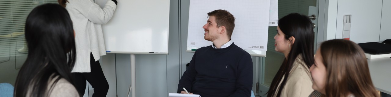 Eine Gruppe von diversen Nachwuchskräften befindet sich in einem modernen Arbeitsraum der KfW. Sie brainstormen zum Thema Vorteile von agilem Arbeiten.