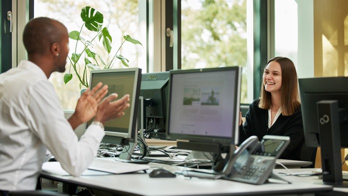 Arbeitssituation im Büro, Kollege und Kollegin sitzen sich gegenüber und sprechen miteinander