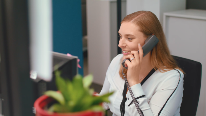 Eine Auszubildende sitzt am Schreibtisch und telefoniert