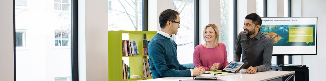 Zwei Auszubildende gehen mit ihrem Mentor eine Präsentation durch