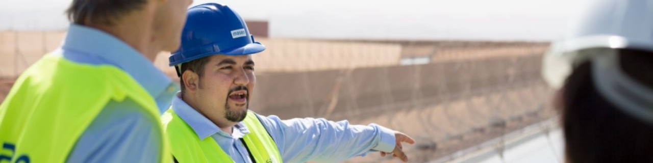 Zwei Vergabemanager besuchen einen Solarpark in Marokko und lassen sich vom Bauleiter über den Projektfortschritt informieren. 