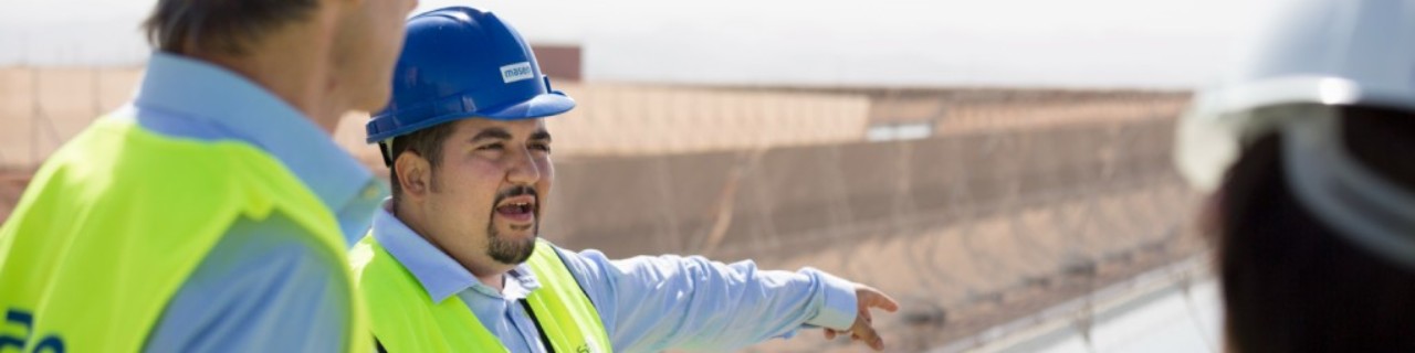 Zwei Vergabemanager besuchen einen Solarpark in Marokko und lassen sich vom Bauleiter über den Projektfortschritt informieren. 
