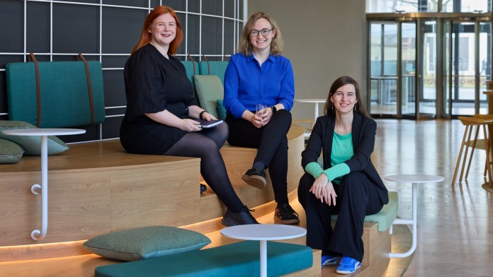 Judith Gudde, Ann-Christin Klein und Lena Bühl, Mitarbeiterinnen der KfW Bankengruppe und Mitglieder des CommunITy Netzwerks sitzen in der Green Loung der KfW und lächeln freundlich in die Kamera. 