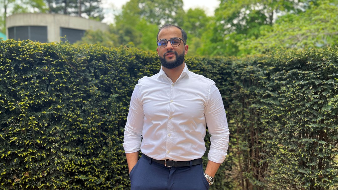 Portraitbild von Omar Elhainouni, Mitarbeiter aus dem IT-Bereich KfW. Er trägt eine Brille, ein weißes Hemd und eine dunkelblaue Anzughose.