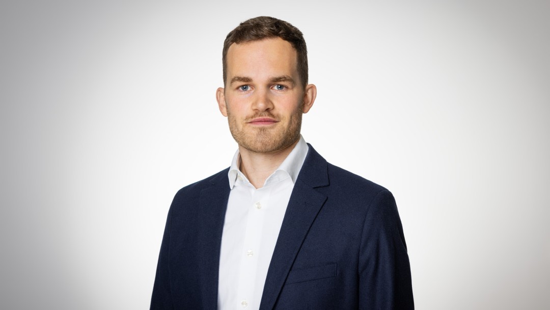 Portraitaufnahme von Friedrich Rothe, Mitarbeiter des Inhouse Consultings der KfW. Er trägt ein weißes Hemd mit einem dunkelblauen Anzug.